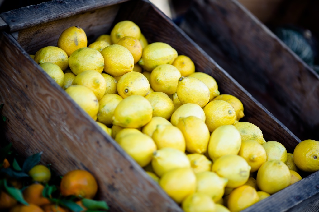 Photo of lemons in a crate at a market stall for a flash fiction story on observing strangers